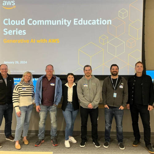 A group of eight people standing in front of a large presentation screen displaying the title "Cloud Community Education Series: Generative AI with AWS" dated January 26, 2024. The individuals are smiling and posing for the photo.
